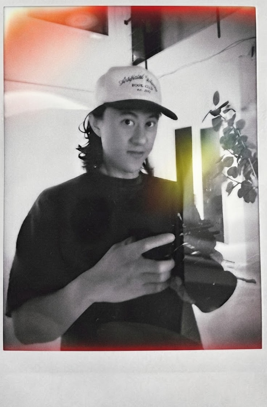 Chris He, photographed in a mirror holding a camera